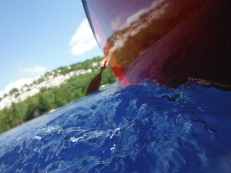 Side of red canoe over extremely blue water