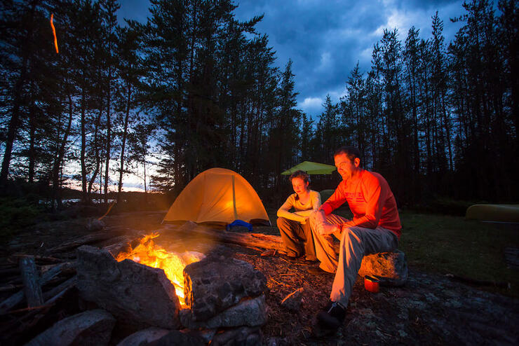 Tent next to a campfire in the woods.
