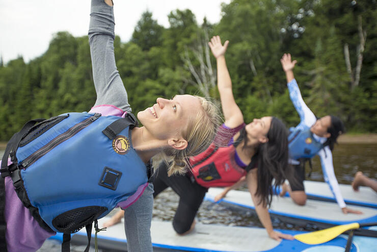Three women doing yoga on paddleboards