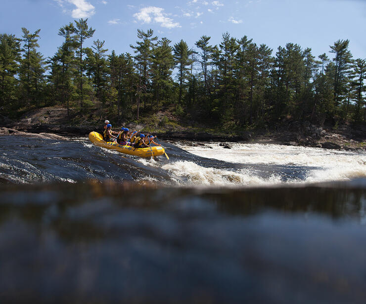 Group in a yellow raft gong down the rapids