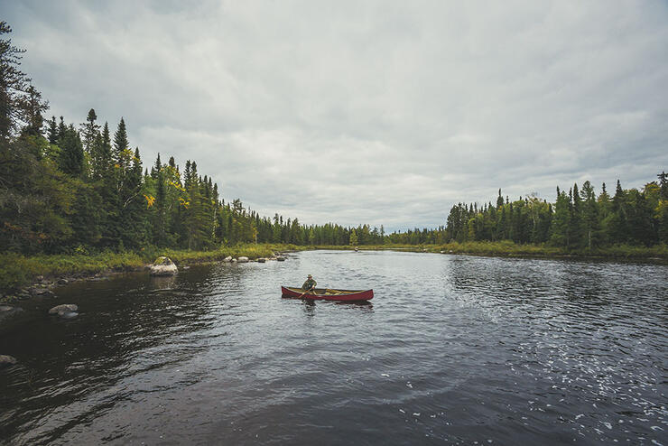 Person in a red canoe paddling a river