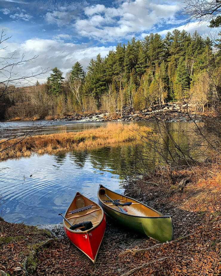 Two canoes sitting at edge of water in the fall