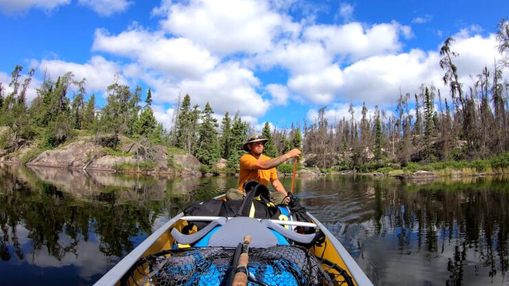 Man paddling in stern of canoe.