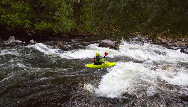 Whitewater kayaker playing in rapids.