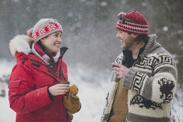 A man and a woman in winter clothing drinking a cup of hot chocolate 