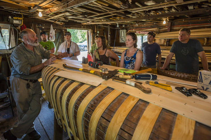 Man repairing a cedar strip canoe in a workshop