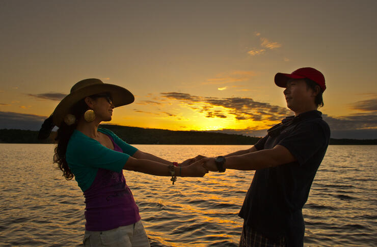 Couple holding hands beside a lake at sunset.