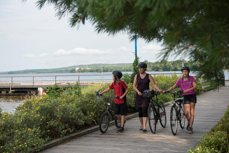 Family walking bikes on boardwalk.