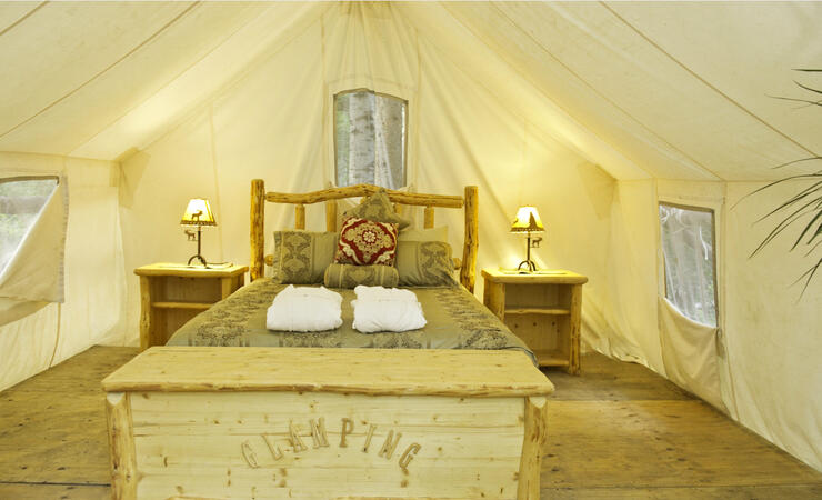 Inside of a prospector tent with wooden bed and nice bedding