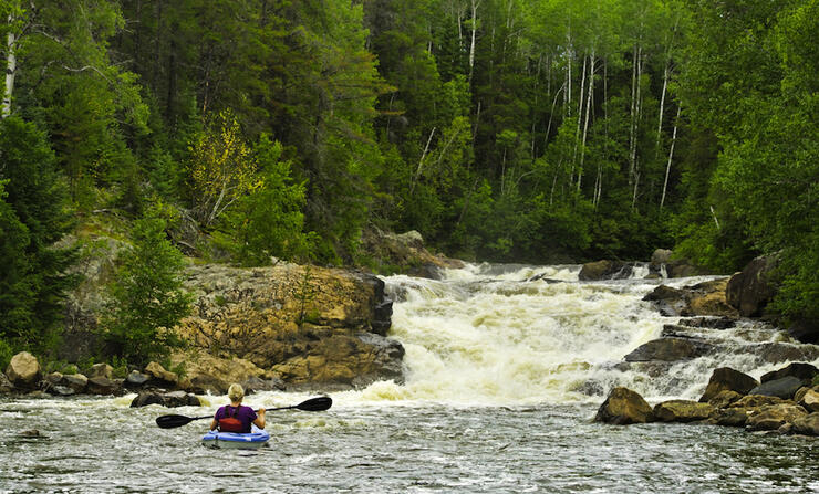 Kayaking paddling towards a small waterfalls.