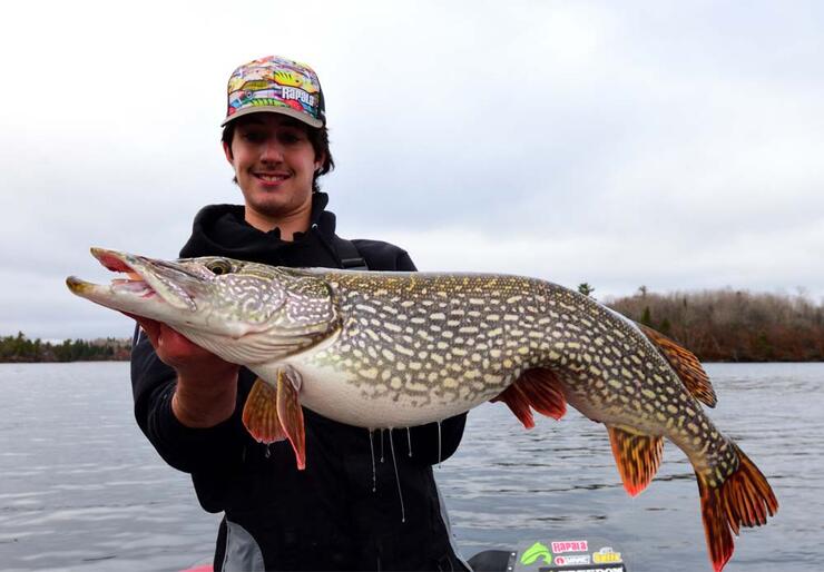 young angler holding northern pike