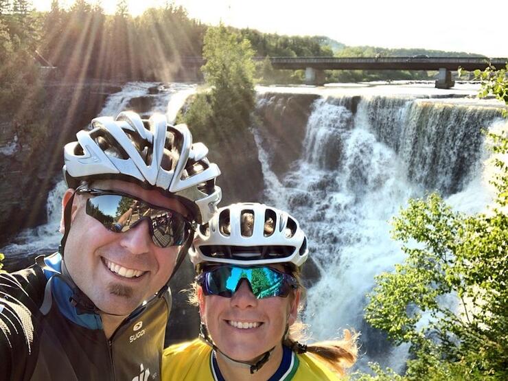Two cyclists standing in front of waterfall