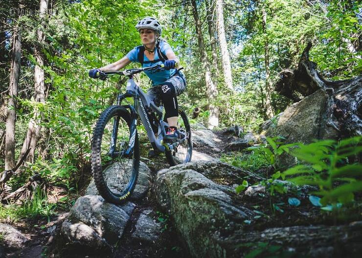 Woman on mountain bike going down rocky feature