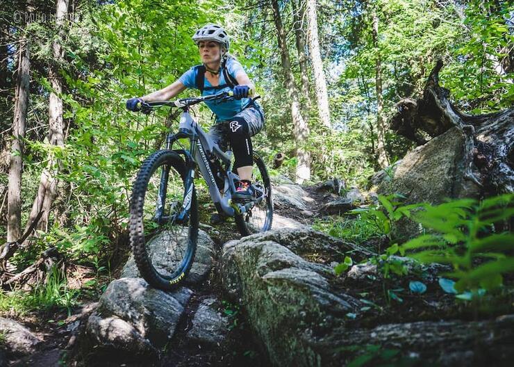 Woman on mountain bike going down rocky feature