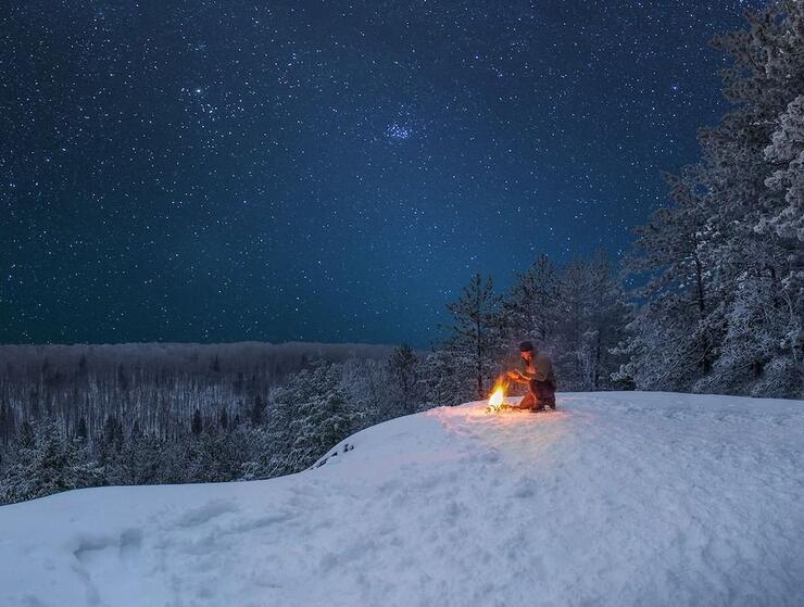 Someone building a fire in the winter at edge of cliff