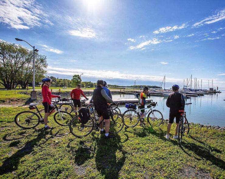 Cyclists gathered on grass next to harbour