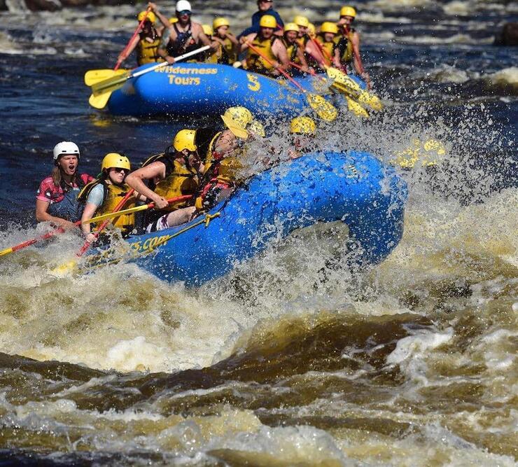 Two blue rafts crashing through waves on river