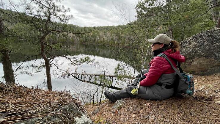 angler sitting beside lake with fly rod